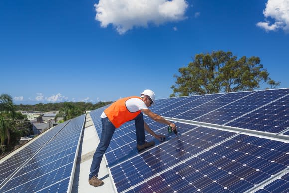 A worker installing rooftop solar panels.