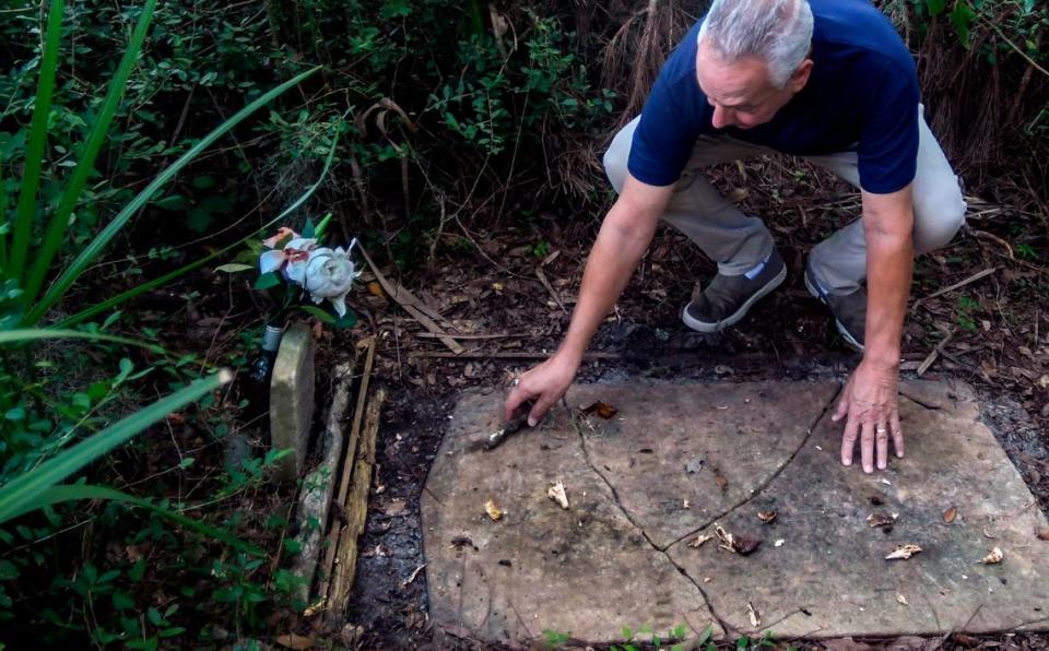 Cast in the shadow of the Cherry Hill Plantation live oak estimated to be more than 3 centuries old, Chuck Yahres clears debris from the grave marker of Mary Pope at the base of the tree on Sept. 21, 2022, in the town of Port Royal. Drew Martin/dmartin@islandpacket.com