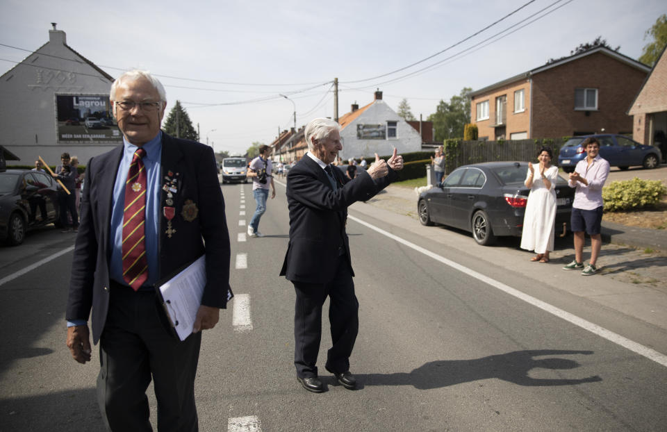 British RAF veteran George Sutherland, 98, right, gives the thumbs up to people who came out to cheer him on during his VE Day charity walk to raise funds for Talbot House in Poperinge, Belgium, Friday, May 8, 2020. Sutherland walked from the Lijssenthoek war cemetery to Talbot house to raise money for the club which is currently closed due to coronavirus lockdown regulations. The club, founded in 1915 was a place for British soldiers to rest during both the First and Second World Wars. (AP Photo/Virginia Mayo)