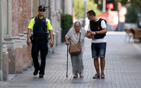 Policemen accompany an elderly woman near a cordoned off area - Credit:  PAU BARRENA