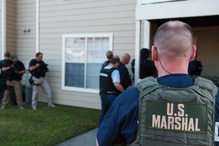 U.S. Marshals prepare to enter a building in this public domain photo from 2015.