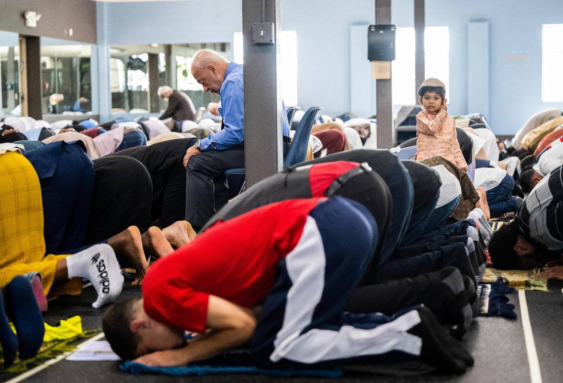 A child stands within a group of men as they pray during a prayer led by Imam Abdulhakim Mohammed for a celebration of the Islamic holiday, Eid al-Adha, at what will soon be the new Islamic Center on Montana Avenue in Tacoma, on Saturday, July 9, 2022.