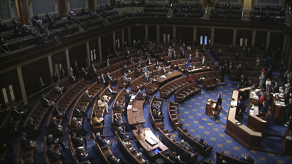 In this image from video, members of the House practice social distancing as they sit on the floor and in the public gallery above during debate on the coronavirus stimulus package on the floor of the House of Representatives at the U.S. Capitol in Washington, Friday, March 27, 2020. (House Television via AP)