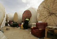 A Bulgarian woman looks inside her wine vat home in Socuellamos, central Spain, October 2, 2007. About 40 people living in this makeshift camp. At night they sleep in 20 or so overturned wine vats -- car-sized concrete barrels dumped on the outskirts of Socuellamos, a farming community in the hot and dusty region of Castilla-La Mancha. Picture taken October 2, 2007.