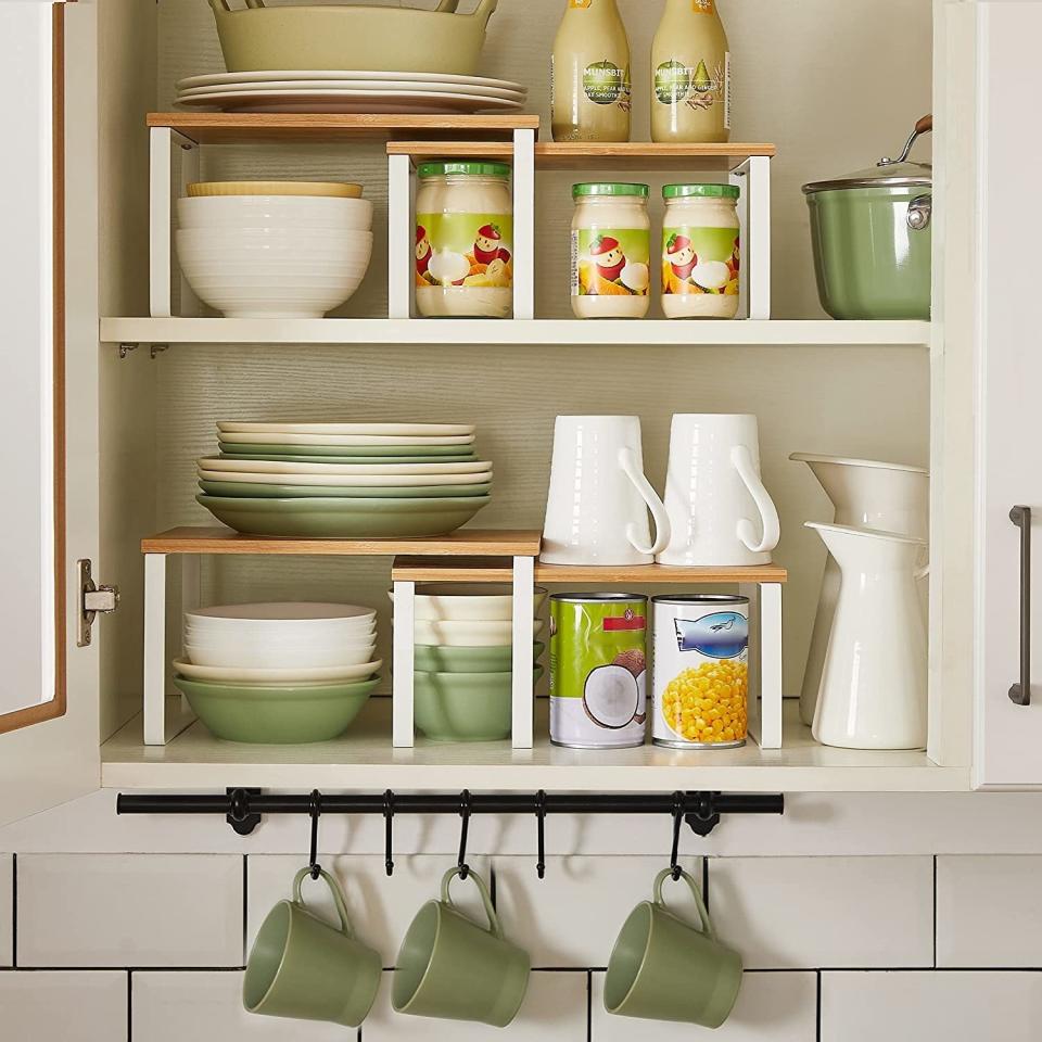 the white organizers in a cabinet holding plates, bowls, and mugs.