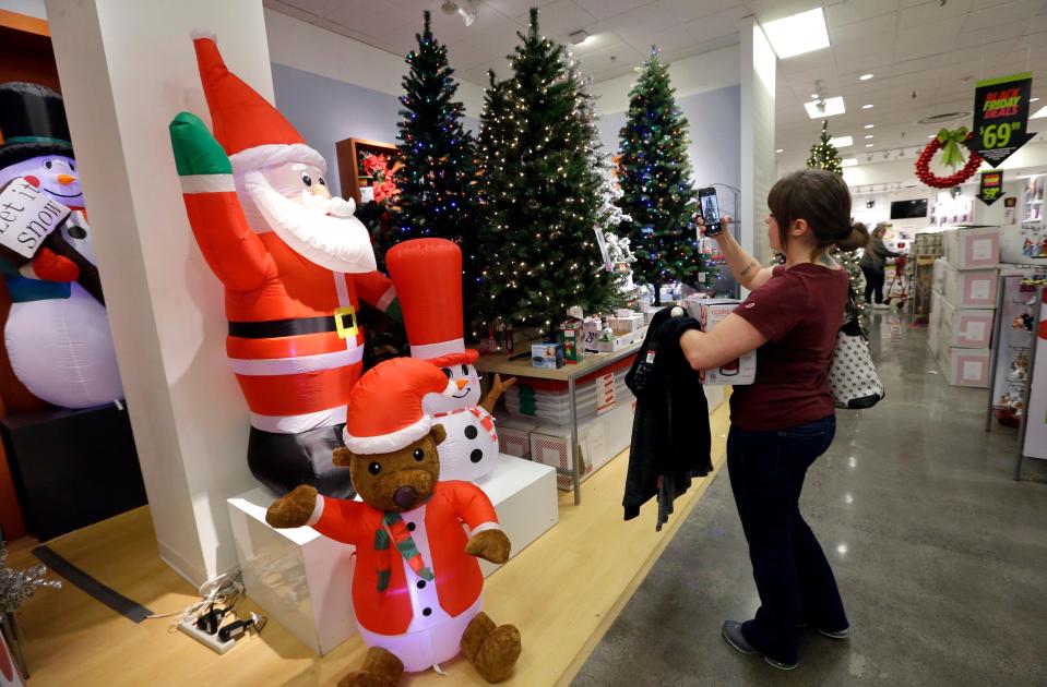 A woman takes photos of artificial Christmas trees while shopping in Seattle.