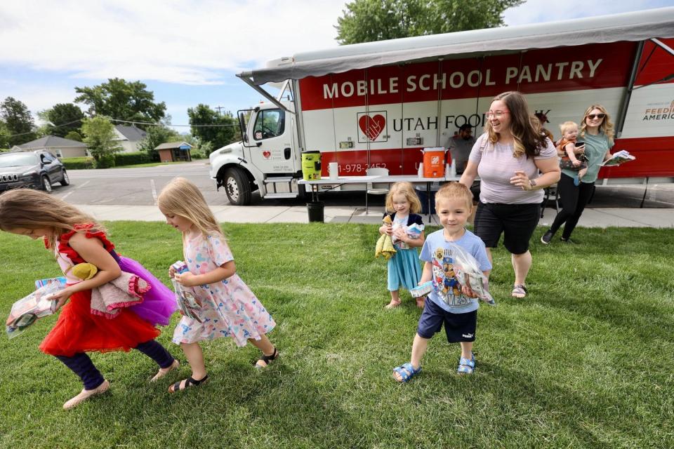 Kids run with their meals from the Utah Food Bank at Pleasant Grove Downtown Park on Wednesday. The Utah Food Bank launched another year of their Summer Food Service Program to help feed children during the summer months.