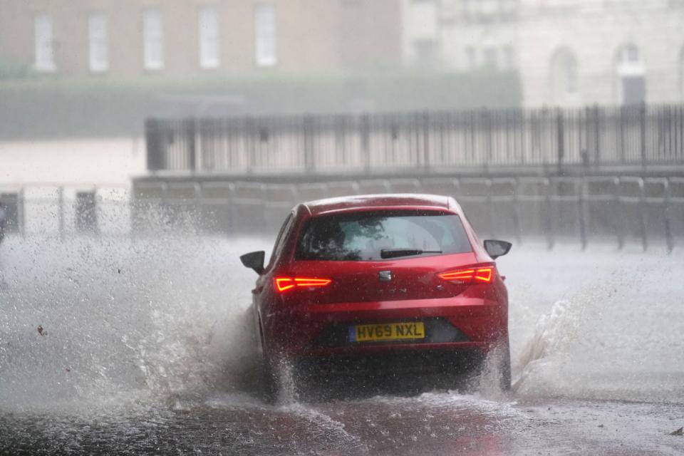 A car drives through flood water in Horse Guards Road in central London (Victoria Jones/PA) (PA Wire)