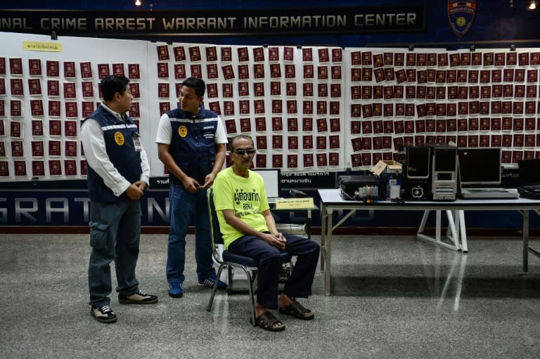 Abdullah Ghani Bhori (R), a Pakistani cohort of Iranian passport forger 'The Doctor' Hamid Reza Jafary, sits on a chair surrounded by fake passports and forgery materials at the Immigration Detention Centre in Bangkok