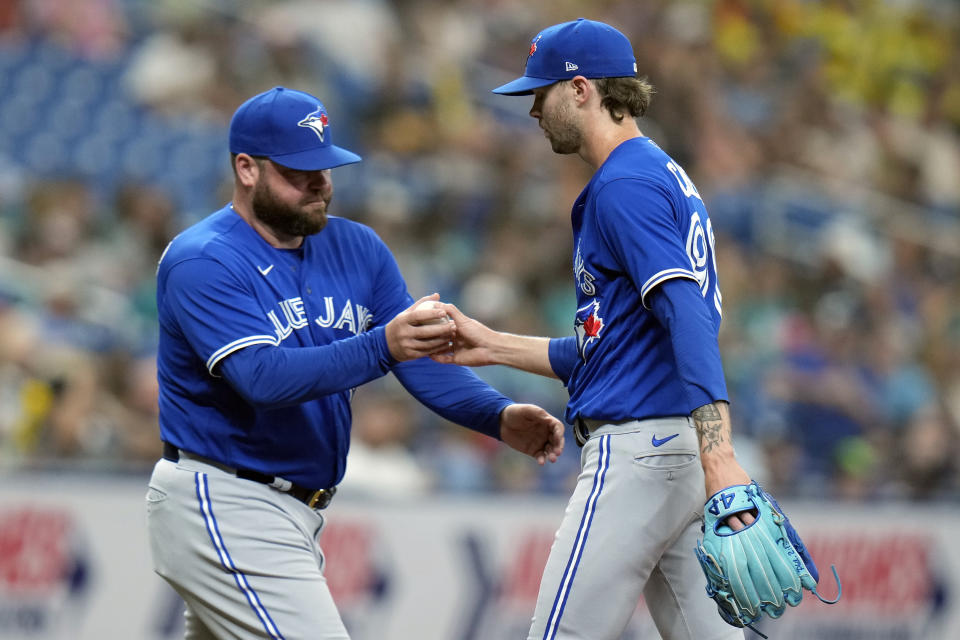 Toronto Blue Jays relief pitcher Adam Cimber, right, hands the ball to interim manager John Schneider as he is taken out of the game against the Tampa Bay Rays during the sixth inning of a baseball game Wednesday, Aug. 3, 2022, in St. Petersburg, Fla. (AP Photo/Chris O'Meara)