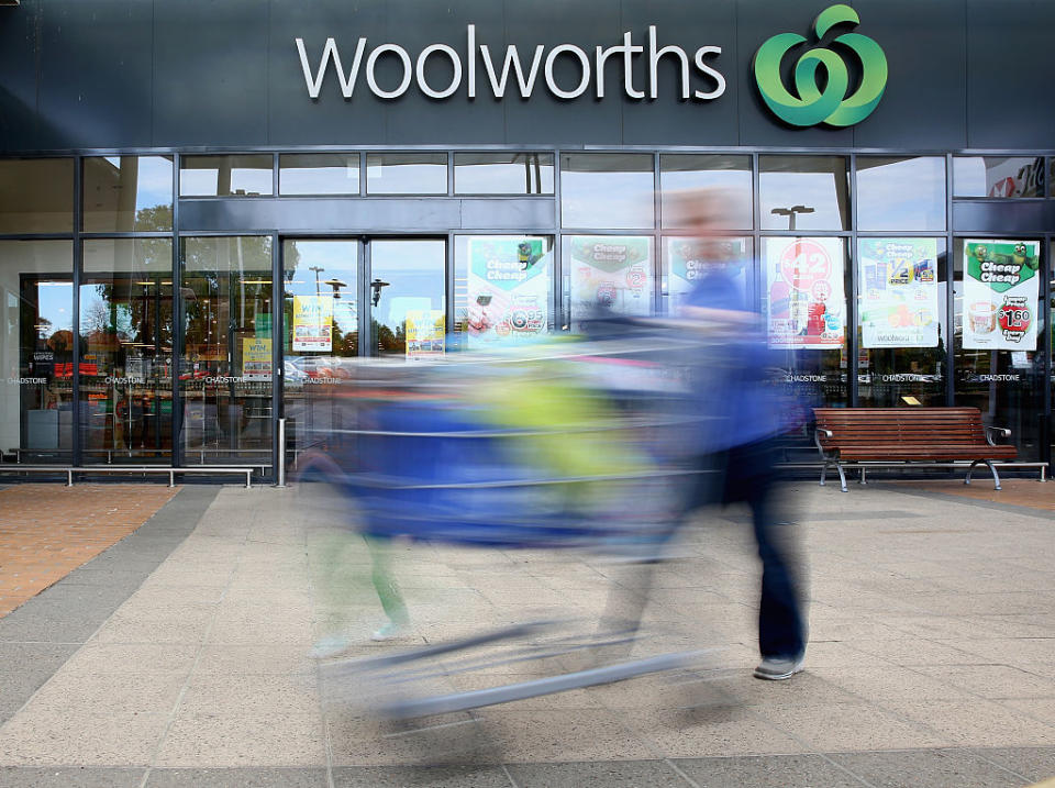 A shopper with a trolley rushes past a Woolworths supermarket. 