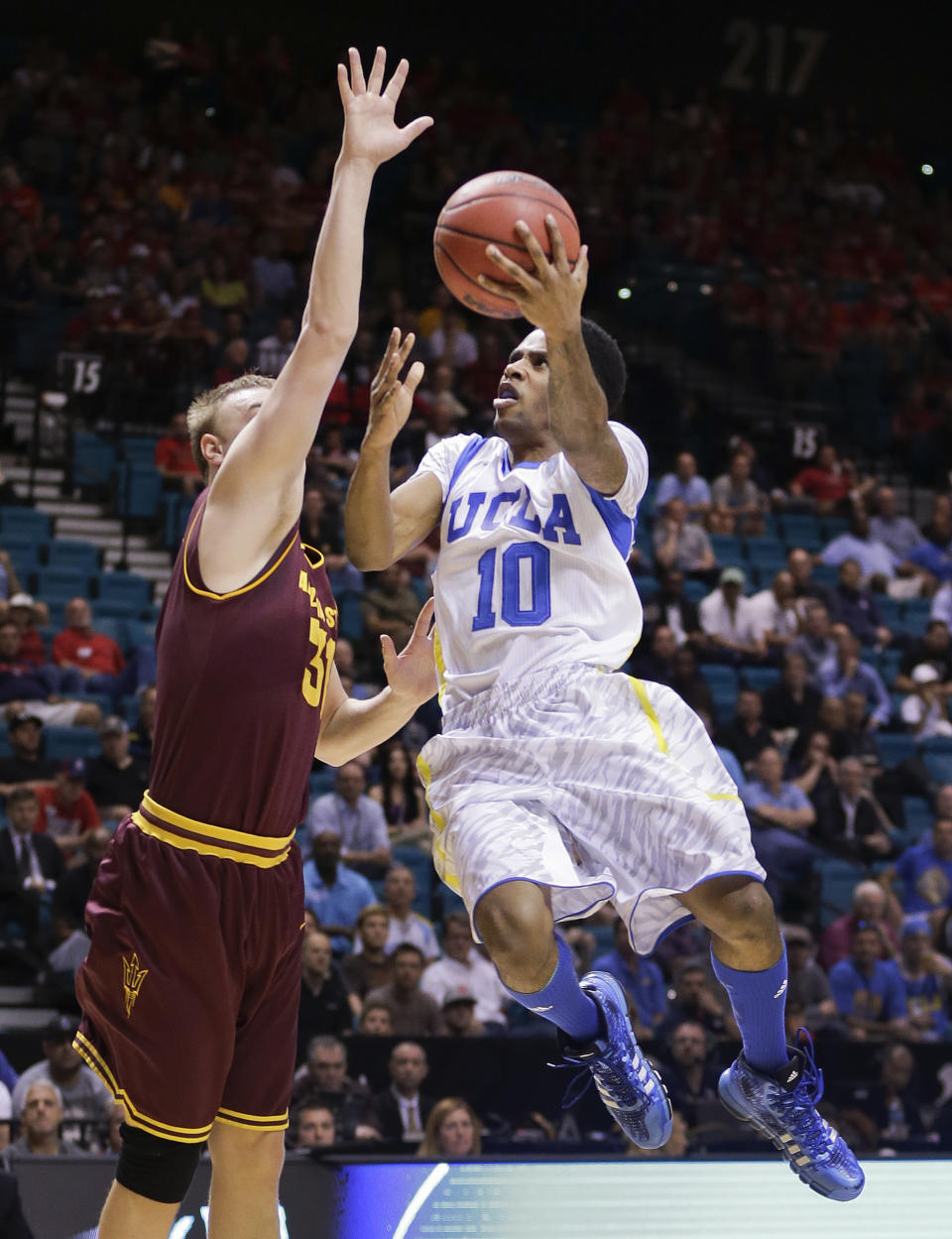 FILE - This March 14, 2013 file photo shows UCLA's Larry Drew II (10) as he goes up for a shot against Arizona State's Jonathan Gilling during the first half of a Pac-12 men's tournament NCAA college basketball game in Las Vegas. The neon-colored jerseys and camouflage-covered shorts debuted by six teams in their post-season conference championships ahead of the NCAA men's basketball tournament weren't well received in the press and social media. The changes happened to be in line with fashion runways and in recreational athleticwear, where highlighter brights and creative camo have been bona fide trends, and alternate uniforms have become part of the college football and basketball landscape, but on the court, these uniforms still made fans cringe. (AP Photo/Julie Jacobson, file)