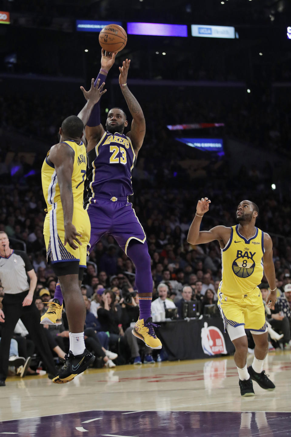 Los Angeles Lakers' LeBron James (23) shoots between Golden State Warriors' Eric Paschall, left, and Alec Burks (8) during the second half of an NBA basketball game Wednesday, Nov. 13, 2019, in Los Angeles. (AP Photo/Marcio Jose Sanchez)