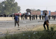 Police officers chase supporters of Tehreek-e-Labiak Pakistan, a radical Islamist party, during their protest march toward Islamabad, on a highway in the town of Sadhuke, in eastern Pakistan, Wednesday, Oct. 27, 2021. Violence at the anti-France Islamist rally in Sadhuke left at least one police officer and two demonstrators dead. ​They demanded the expulsion of France's envoy to Pakistan over publication of caricatures of Islam's Prophet Muhammad in France. (AP Photo/K.M. Chaudary)