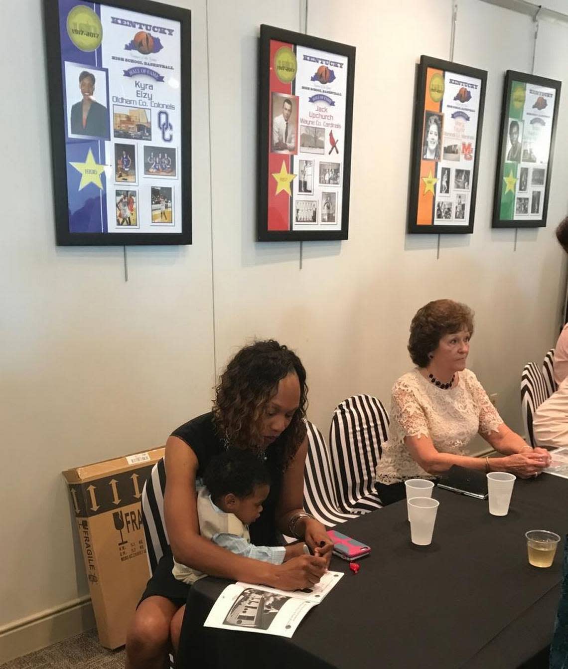 Former Oldham County girls’ basketball star and current University of Kentucky women’s coach Kyra Elzy held her son, Jackson, while signing autographs at the reception before the 2017 Kentucky High School Basketball Hall of Fame induction. Mark Story/mstory@herald-leader.com