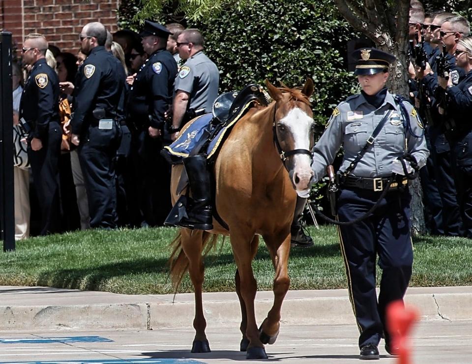 A horse is led through the crowd Monday as part of the riderless horse ceremony after the funeral for Edmond police Sgt. C.J. Nelson at Crossings Community Church in Oklahoma City.