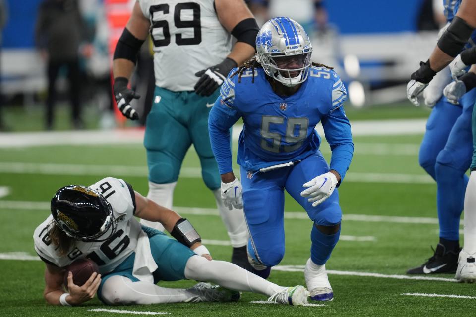 Jacksonville Jaguars quarterback Trevor Lawrence holds his left leg after being sacked by Detroit Lions linebacker James Houston (59) during the first half of an NFL football game, Sunday, Dec. 4, 2022, in Detroit. (AP Photo/Paul Sancya)