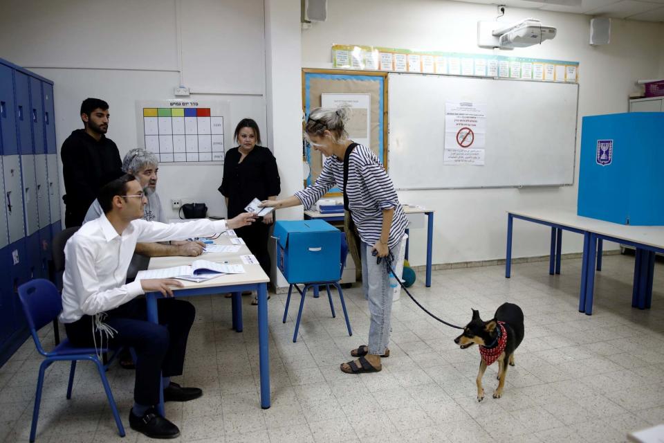 A woman holds her dog's leash as she prepares to vote in Israel's parliamentary election, at a polling station in Tel Aviv. (REUTERS)