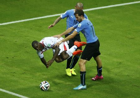 Costa Rica's Joel Campbell (L) is fouled by Uruguay's Maximiliano Pereira (back) next to teammate Cristian Rodriguez during their 2014 World Cup Group D soccer match at the Castelao arena in Fortaleza, June 14, 2014. REUTERS/Mike Blake