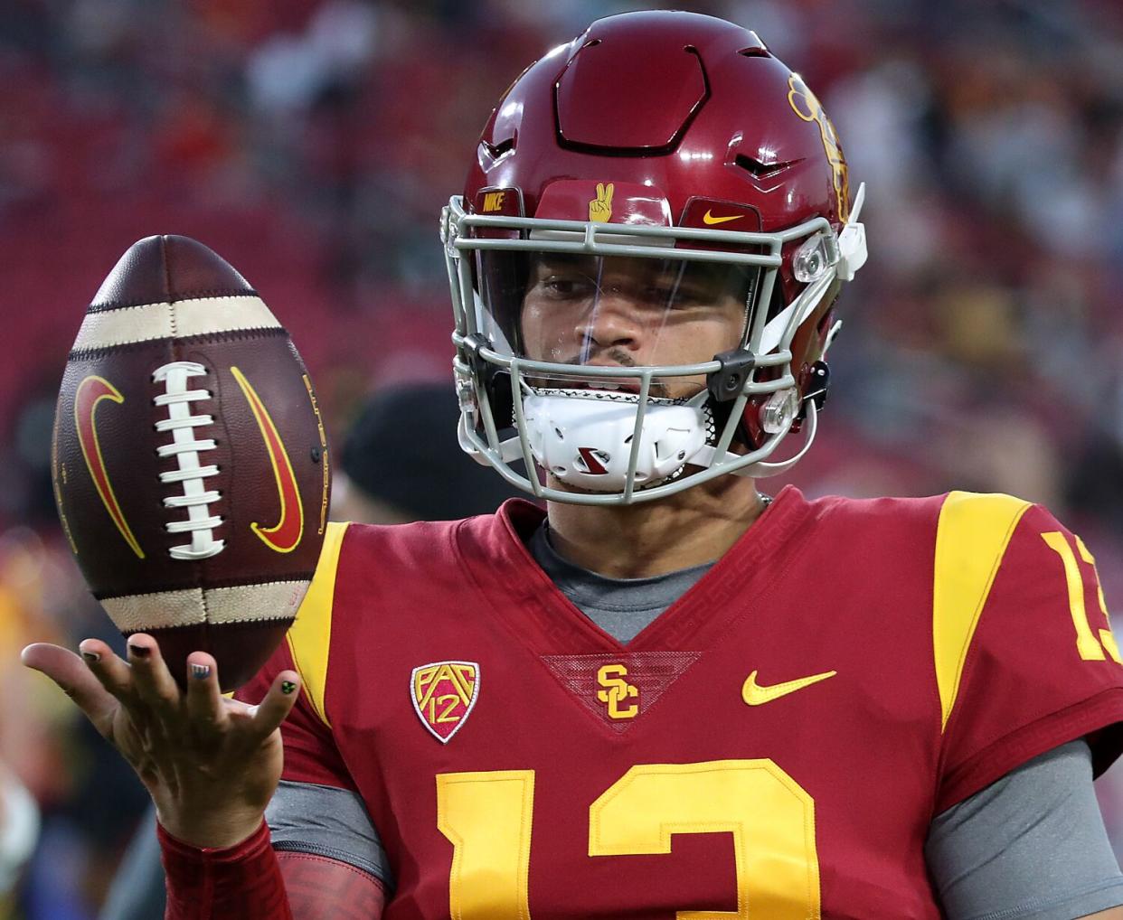 USC quarterback Caleb Williams holds a football upright.