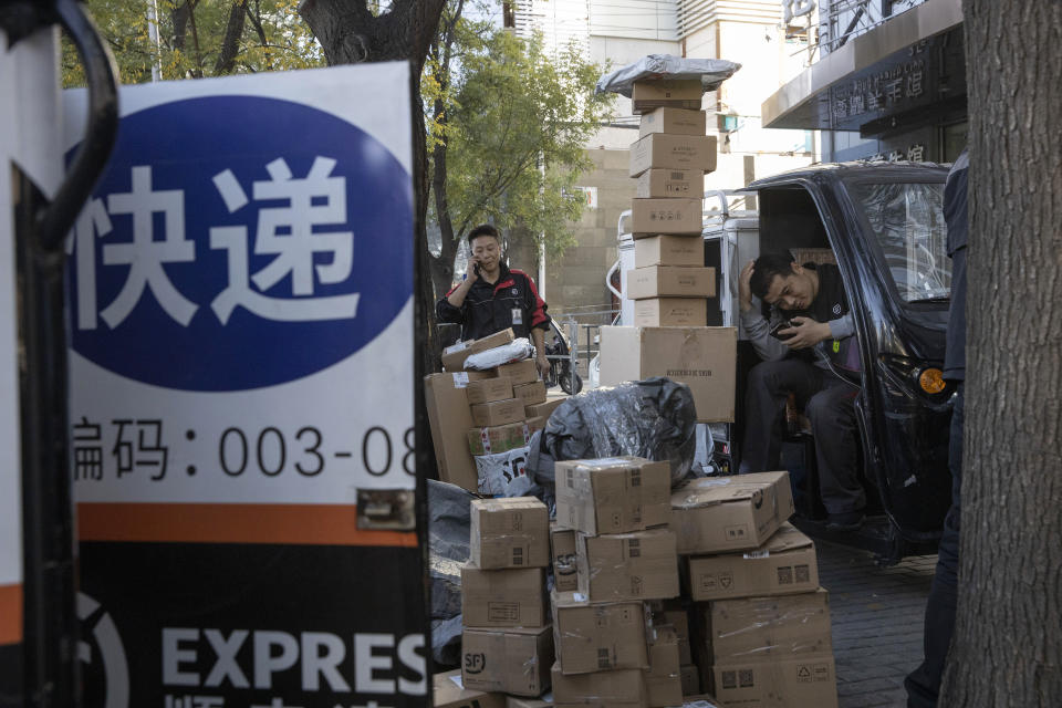 ADDS TRANSLATION - Delivery men wait to distribute parcels on the streets of Beijing on Monday, Nov. 11, 2019. Chinese e-commerce giants Alibaba and JD.com reported a total of more than $50 billion in sales on Monday in the first half of Singles Day, an annual marketing event that is the world's busiest online shopping day. The sign reads "Delivery." (AP Photo/Ng Han Guan)