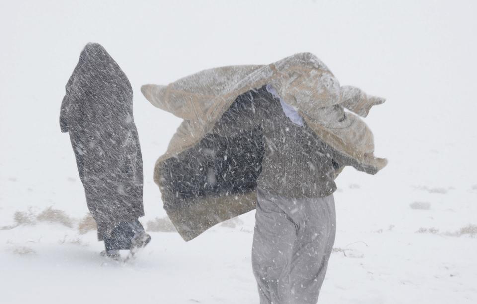 Saudi men walk along a snow-covered road during a snowstorm in Alkan village, west of Saudi Arabia December 13, 2013. REUTERS/Mohamed Alhwaity (SAUDI ARABIA - Tags: ENVIRONMENT SOCIETY)