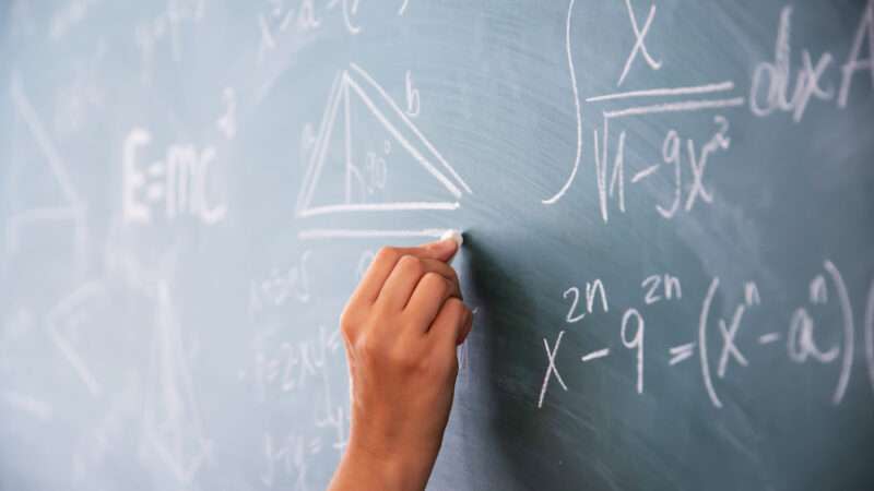 Hand writing math calculations on a chalkboard