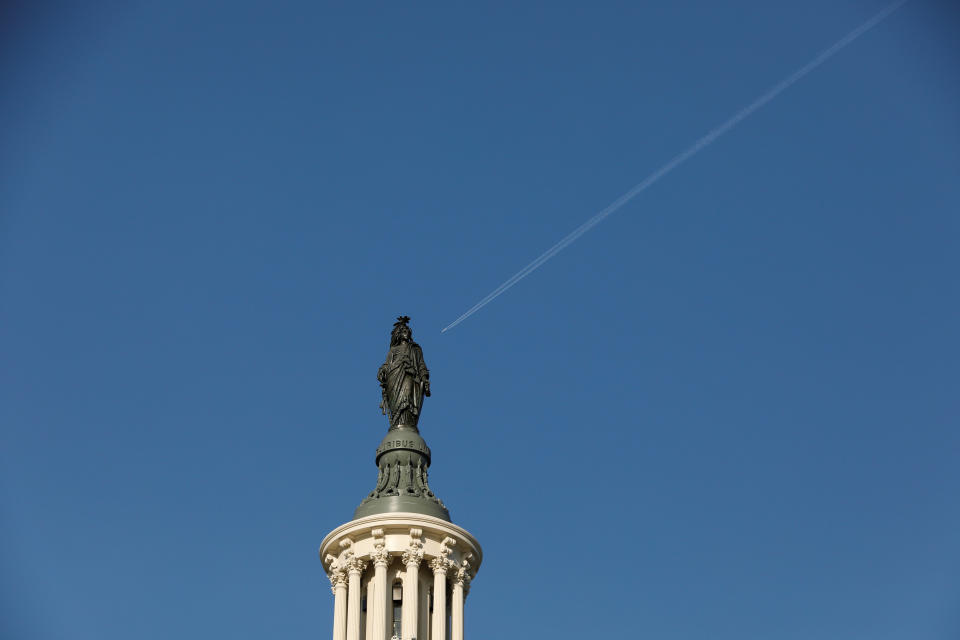 An airplane flies behind the Statue of Freedom, atop of the U.S. Capitol Building, as Mayor Muriel Bowser declared a State of Emergency due to the coronavirus disease (COVID-19), on Capitol Hill in Washington