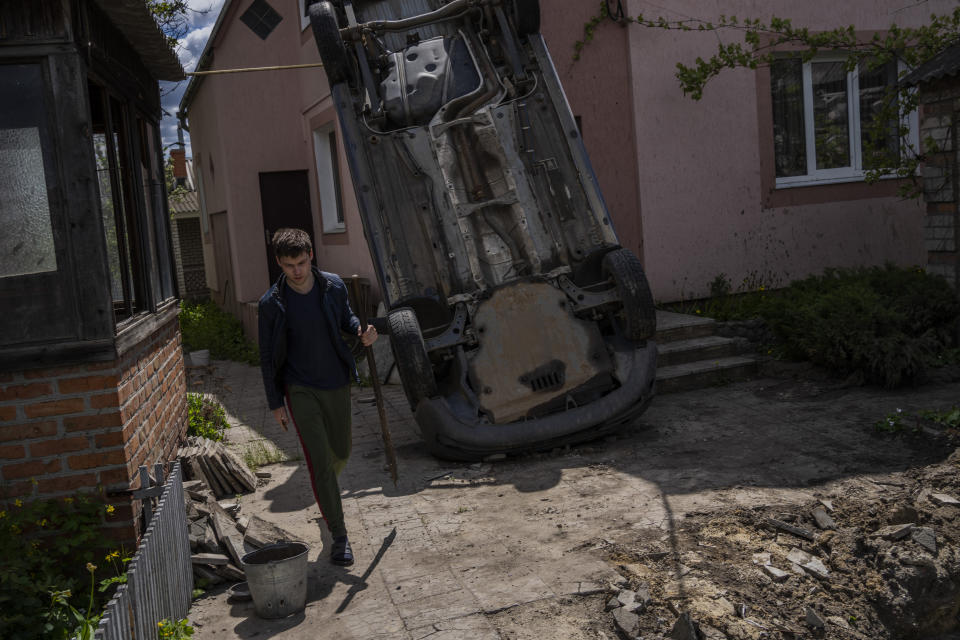 A resident carries a shovel to clear the rubble from his house damaged during a shelling in Kharkiv, Ukraine, Monday, May 16, 2022. (AP Photo/Bernat Armangue)