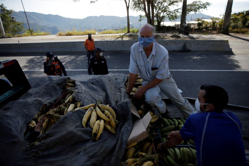 Traveling over plantains, a man wearing a protective mask passes through a checkpoint after the start of quarantine in response to the spreading of coronavirus (COVID-19) in Caracas