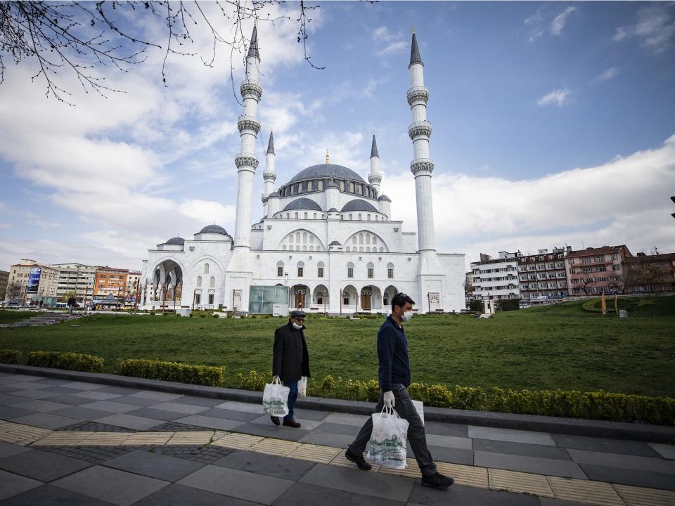 People wearing mask walk in front of empty Melike Hatun Mosque as people are staying home within measures taken against the coronavirus pandemic in Ankara, Turkey on April 6.