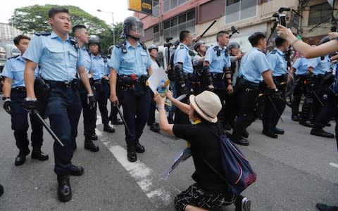 A supporter begs police officer not to attack protesters - Credit: AP