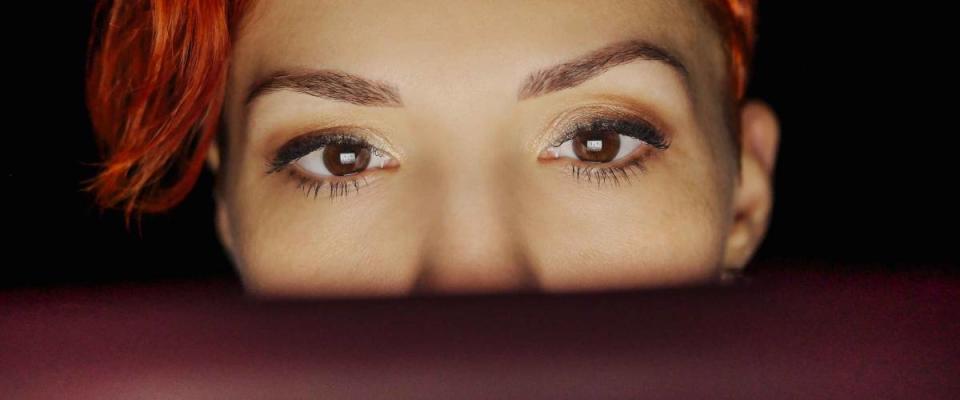 Close-up of beautiful young woman eyes looking at monitor, working on her computer to find insurance discounts.