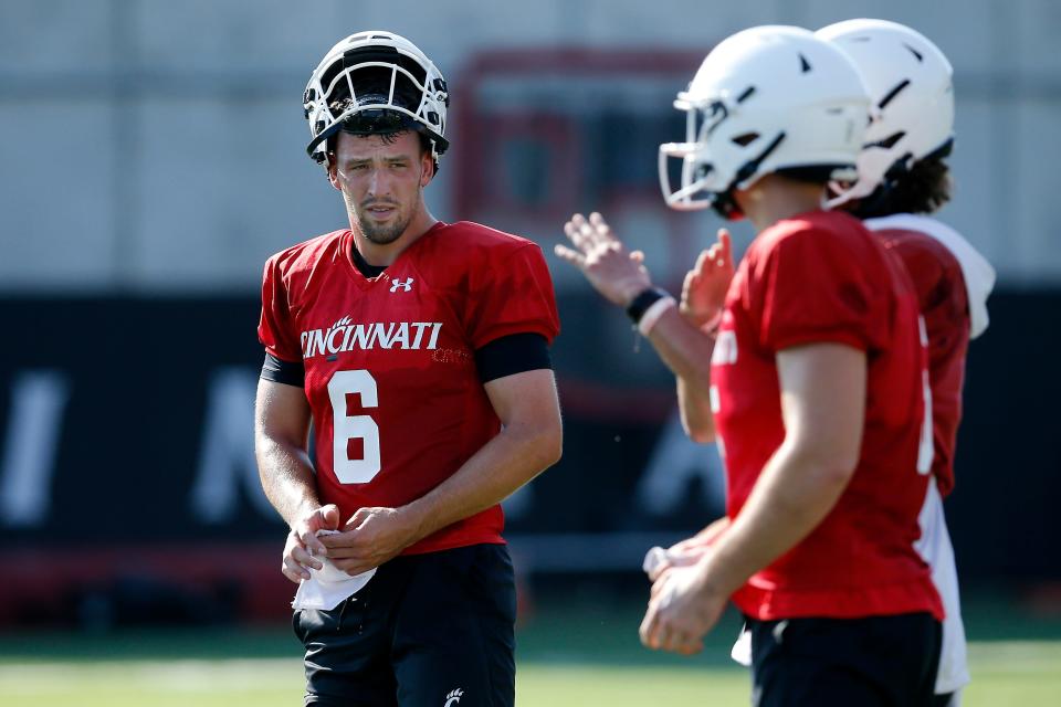 Ben Bryant (6) and the rest of the quarterbacks talk during the first day of preseason training camp at the University of Cincinnati’s Sheakley Athletic Complex in Cincinnati on Wednesday, Aug. 3, 2022.