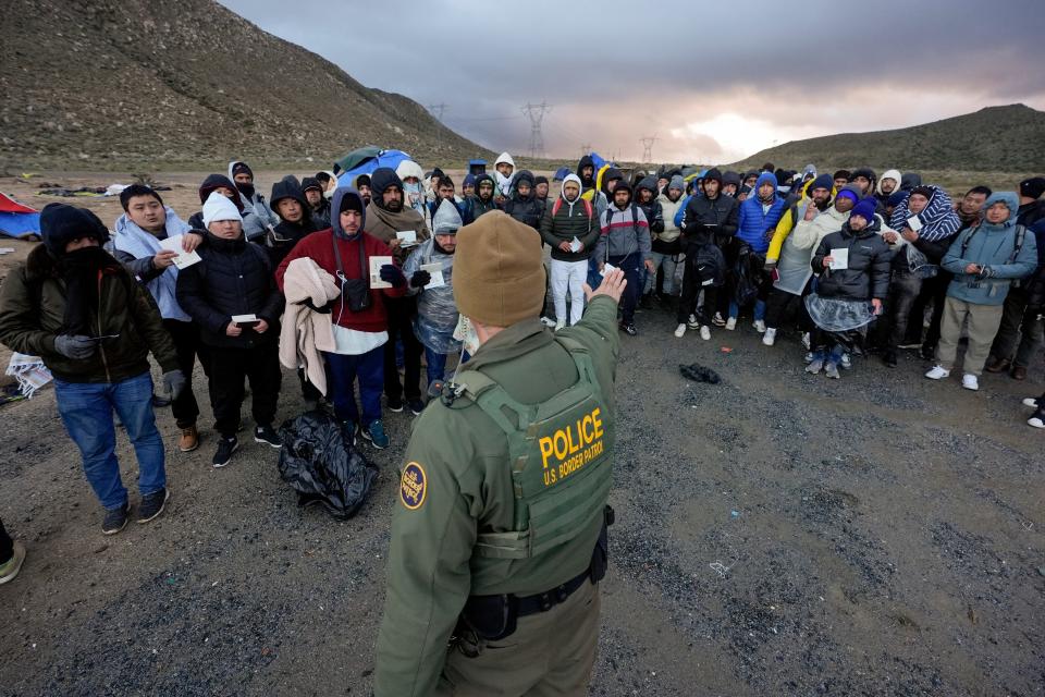 A Border Patrol agent asks asylum-seeking migrants to line up in a makeshift, mountainous campsite after the group crossed the border with Mexico, Friday, Feb. 2, 2024, near Jacumba Hot Springs, Calif. (AP Photo/Gregory Bull) ORG XMIT: CAGB108