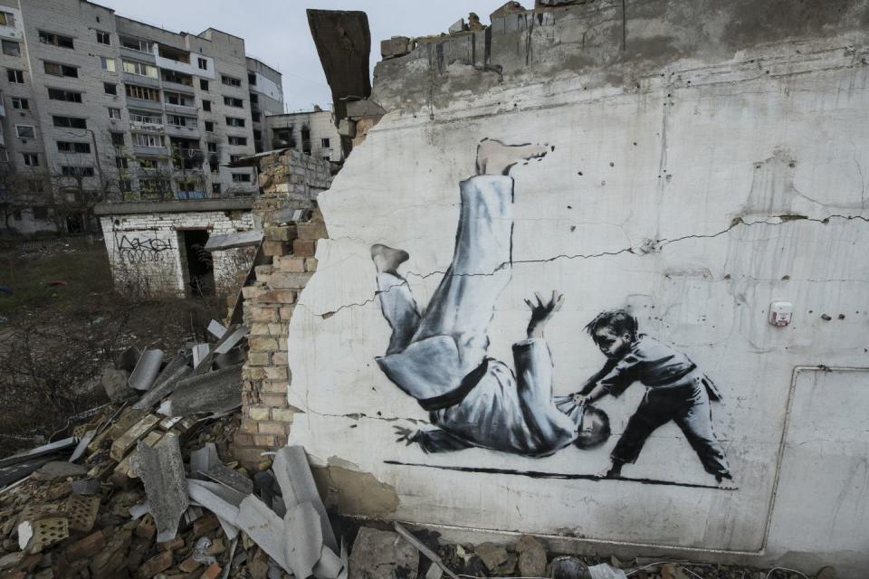 new graffiti in banksy style at the wall of destroyed residental buildings in the towns near kyiv