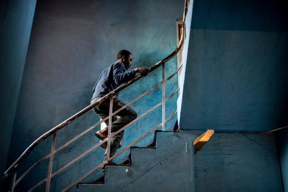 A foreign migrant carries a bucket filled with water as he climbs stairs in a building in the Kwa Mai Mai area in Johannesburg - MARCO LONGARI/AFP via Getty Images