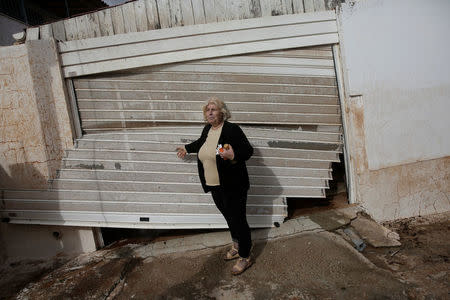 Local Konstantina Louka stands next to her destroyed garage entrance following a heavy rainfall in the town of Mandra, Greece, November 15, 2017. REUTERS/Alkis Konstantinidis