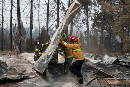 FILE PHOTO: Firefighters move debris while recovering human remains from a trailer home destroyed by the Camp Fire in Paradise, California, U.S., November 17, 2018. REUTERS/Terray Sylvester