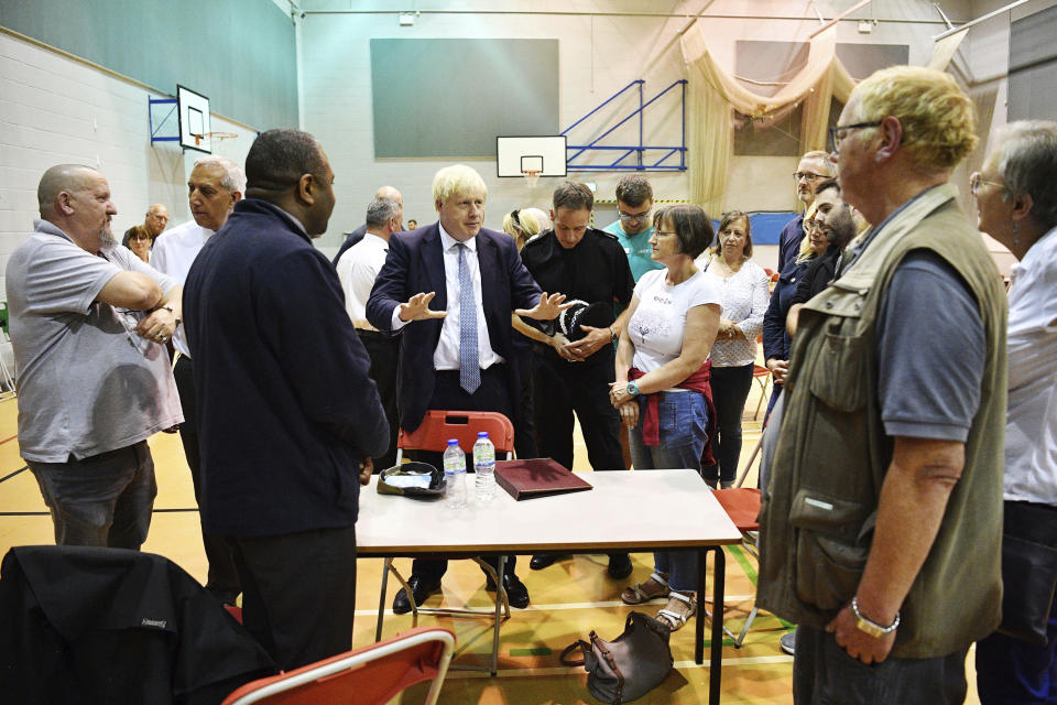 Britain's Prime Minister Boris Johnson meets with rescue crews and local residents during a visit to Chapel-en-le-Frith High School near the village of Whaley Bridge in Derbyshire, England, Friday, Aug. 2, 2019. A British military helicopter dropped sandbags Friday to shore up a reservoir wall as emergency services worked frantically to prevent a rain-damaged dam from collapsing. Engineers said they remain "very concerned" about the integrity of the 19th-century Toddbrook Reservoir, which contains around 1.3 million metric tons (1.5 million (U.S tons) of water. (Leon Neal/Pool photo via AP)