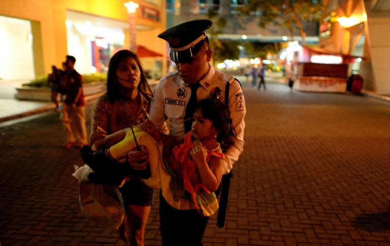 A Philippines shopping mall security officer carries a child out of one of the world's largest shopping malls following an attempted robbery on a jewellery store inside in Manila on March 30, 2014