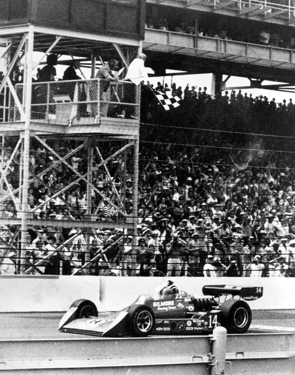 FILE - A.J. Foyt raises his hand in victory as he crosses the finish line in his Gilmore Racing Team Coyote/Foyt with the checkered flag waving above him at the Indy 500-mile race at the Indianapolis Motor Speedway in Indianapolis, Indiana, May 29, 1977. Foyt is the first man to win the Indy 500 four times. He won the race with an average speed of 161.331 miles per hour. (AP Photo/File)