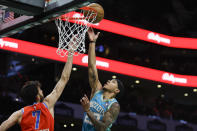 Charlotte Hornets guard Tre Mann, right, shoots over Oklahoma City Thunder forward Chet Holmgren (7) during the first half of an NBA basketball game in Charlotte, N.C., Sunday, April 7, 2024. (AP Photo/Nell Redmond)