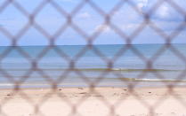 The beach is seen through steel wire net fence in Vung Tau, Vietnam, Monday, Sept. 20, 2021. In Vung Tau, just outside Ho Chi Minh city, streets are sealed and checkpoints are set up to control the movement of people. Barbed wire, door panels, steel sheets, chairs and tables are among materials being used to fence up alleys and isolate neighborhoods.(AP Photo/Hau Dinh)