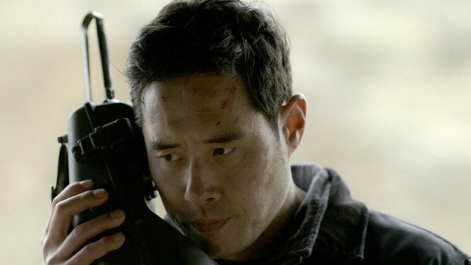 Raymond Lee holding a satellite phone in Quantum Leap as Dr. Ben Song