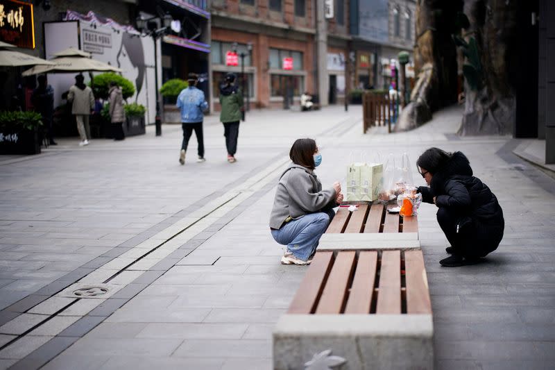 People eat on a bench at a shopping complex in Wuhan