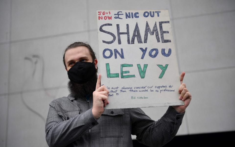 A fan holds a poster reacting to the collapse of the planned creation of a European Super League - AFP