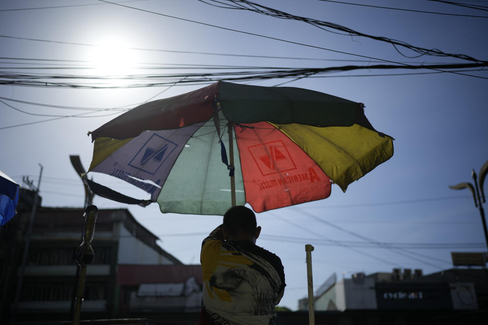 FILE - A vendor prepares his umbrella as hot days continue in Manila, Philippines on April 29, 2024. Sizzling heat across Asia and the Middle East in late April that echoed last year’s destructive swelter was made 45 times more likely in some parts of the continent because of human-caused climate change, a study found. (AP Photo/Aaron Favila, File)