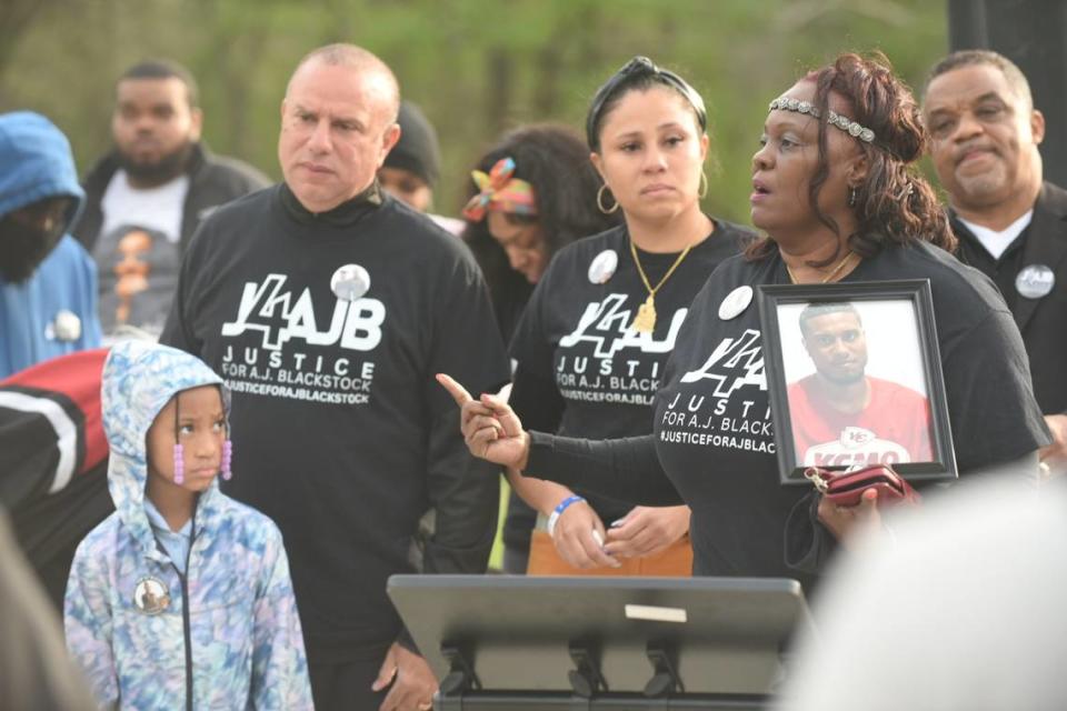 Standing beside family and holding a portrait of her 24-year-old son Adam “AJ” Blackstock Jr., Adrinne Blackstock, right, speaks during a prayer vigil held Monday evening in Kansas City’s Oak Park neighborhood near 43rd Street and Agnes Avenue.