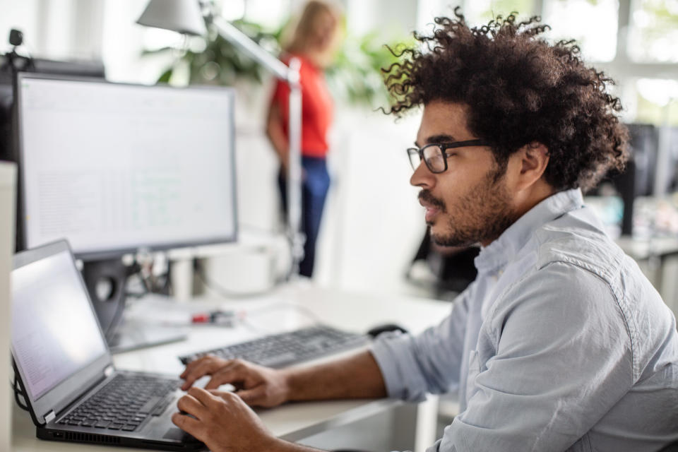 Side view of businessman using laptop at desk in office